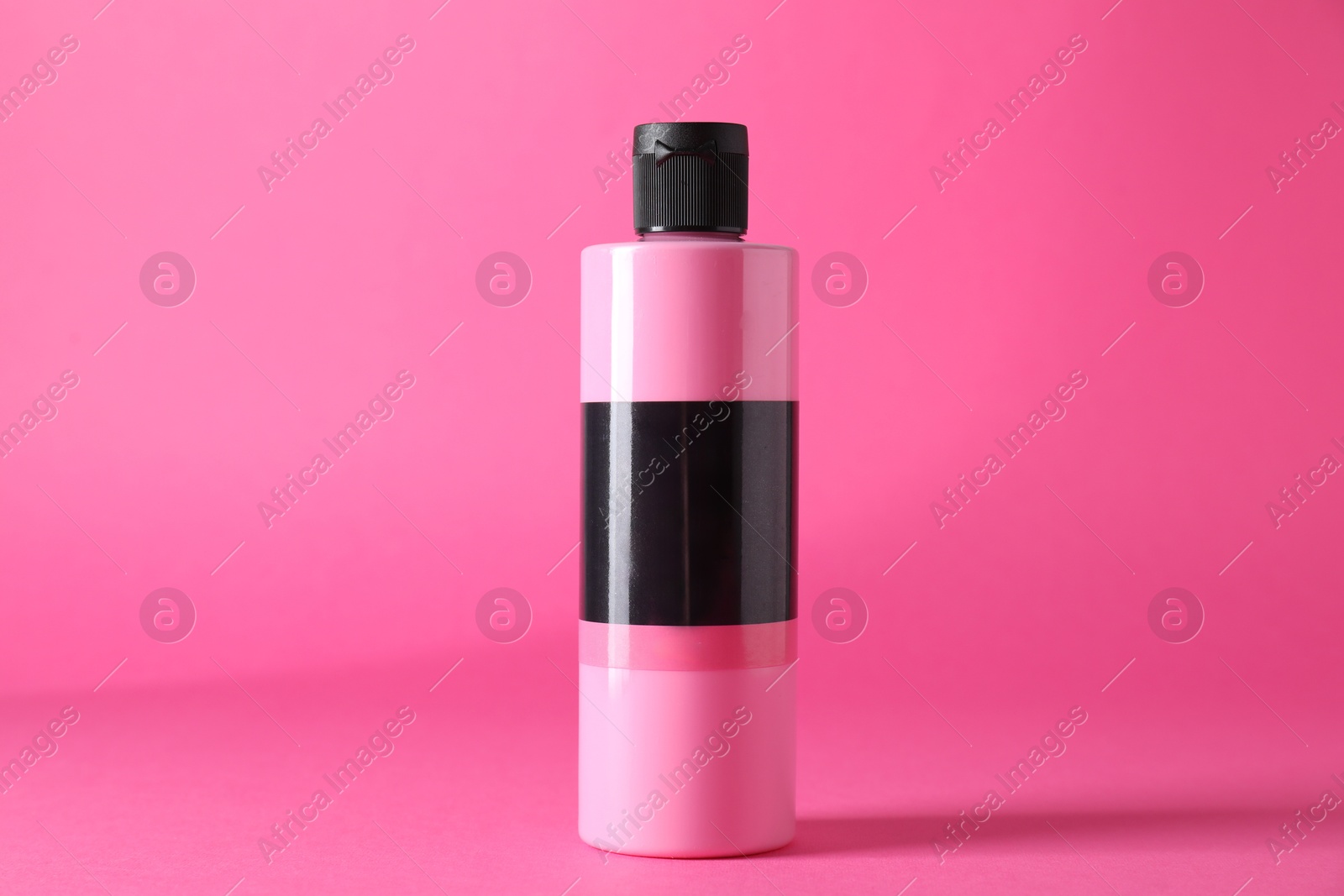 Photo of Acrylic paint in bottle on pink background