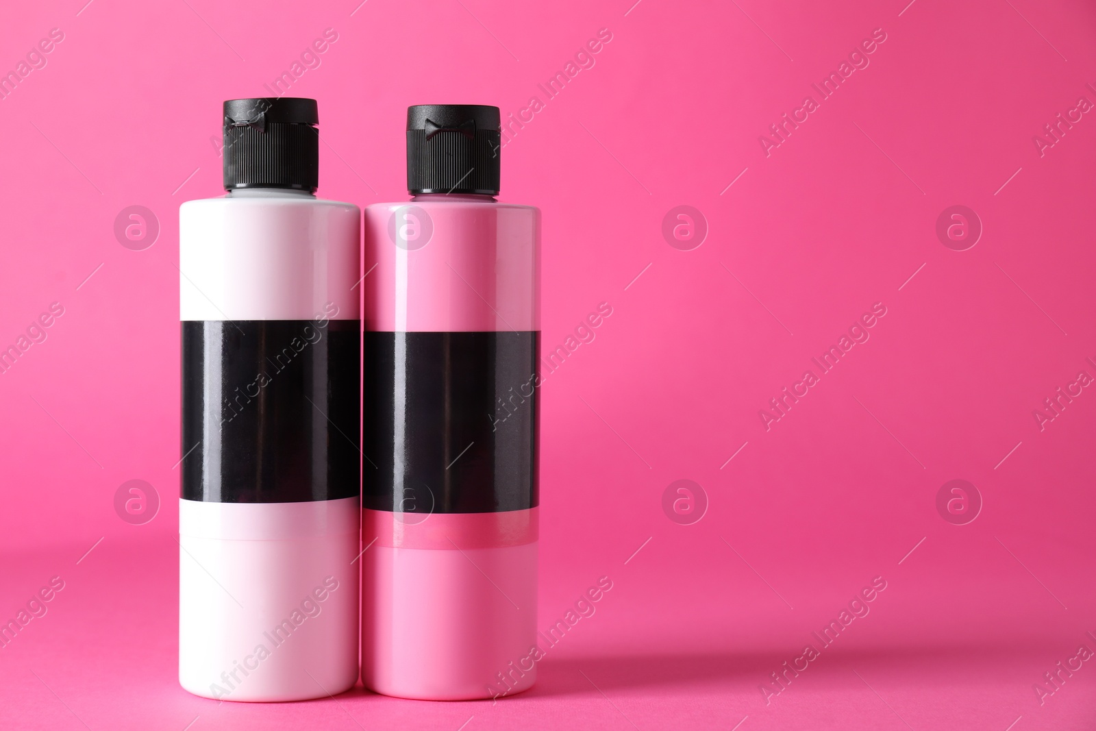 Photo of Acrylic paints of different colors on pink background, space for text