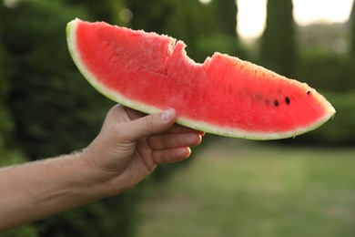 Photo of Man holding slice of juicy watermelon outdoors on sunny day, closeup