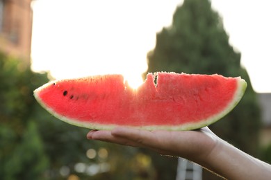 Photo of Man holding slice of juicy watermelon outdoors on sunny day, closeup