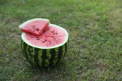 Photo of Cut juicy watermelon on green grass outdoors