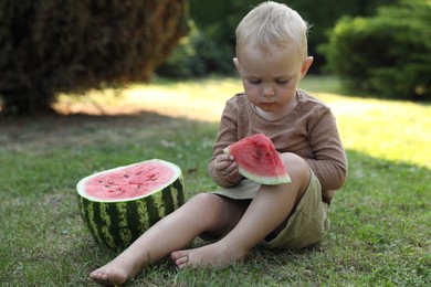 Photo of Cute little baby eating juicy watermelon on green grass outdoors