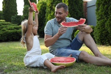 Man and his cute daughter eating juicy watermelon outdoors together