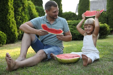 Man and his cute daughter eating juicy watermelon outdoors together