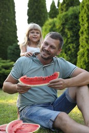 Man and his cute daughter eating juicy watermelon outdoors together