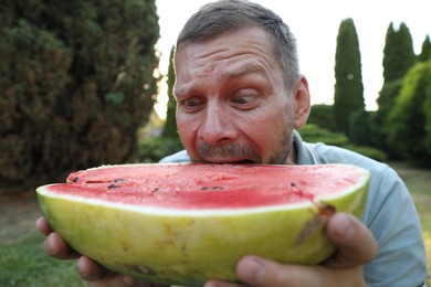 Happy man with half of juicy watermelon outdoors