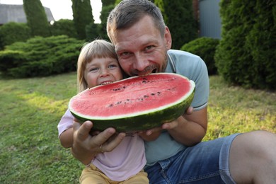 Man and his cute daughter eating juicy watermelon outdoors together