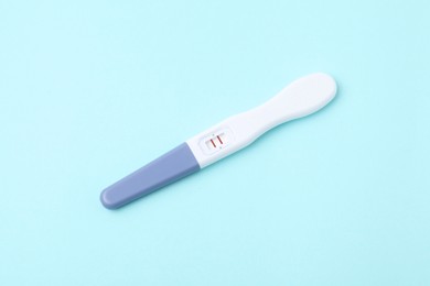 Photo of One pregnancy test on light blue background