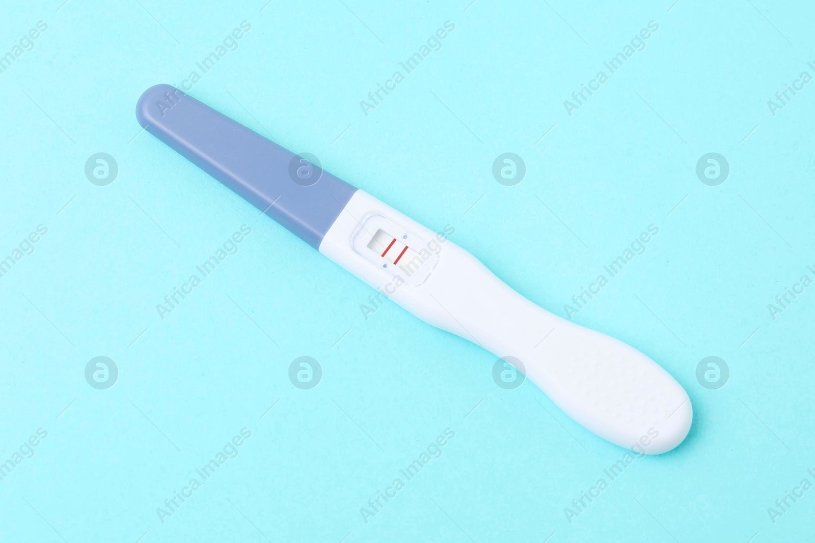 Photo of One pregnancy test on light blue background, closeup