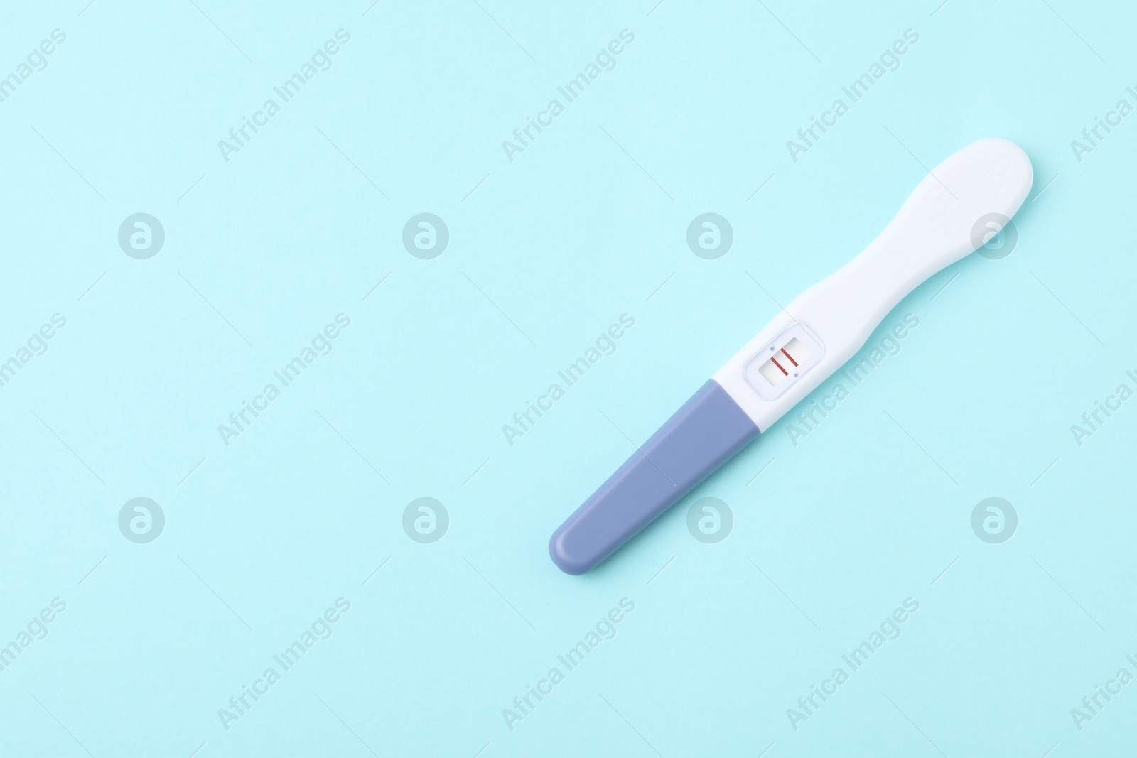 Photo of One pregnancy test on light blue background, top view. Space for text