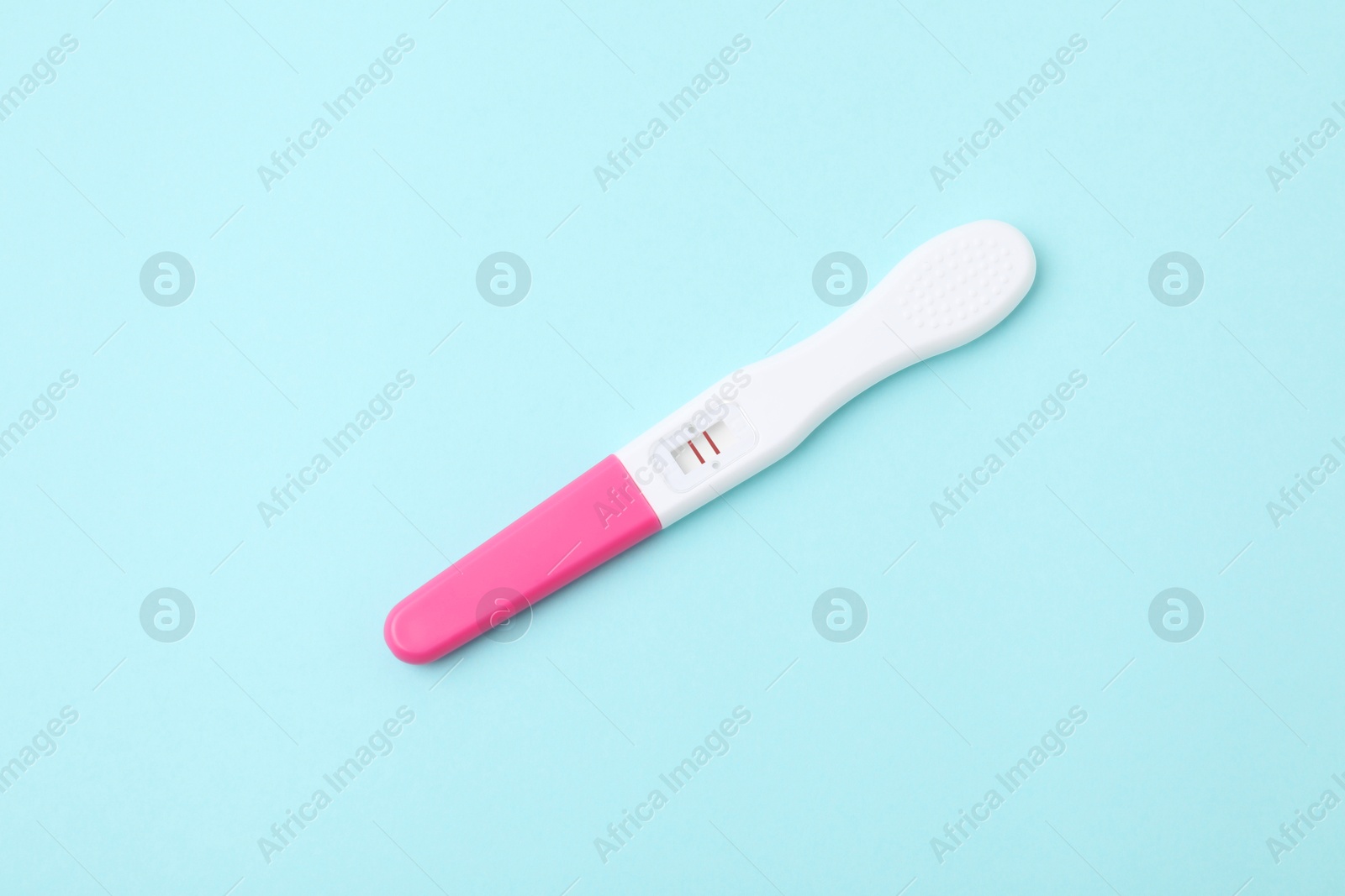 Photo of One pregnancy test on light blue background, above view