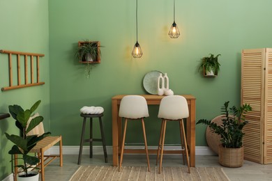 Photo of Bar stools, table and plants in room. Stylish interior design