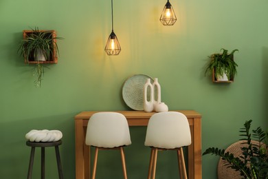 Photo of Bar stools, table and plants in room. Stylish interior design