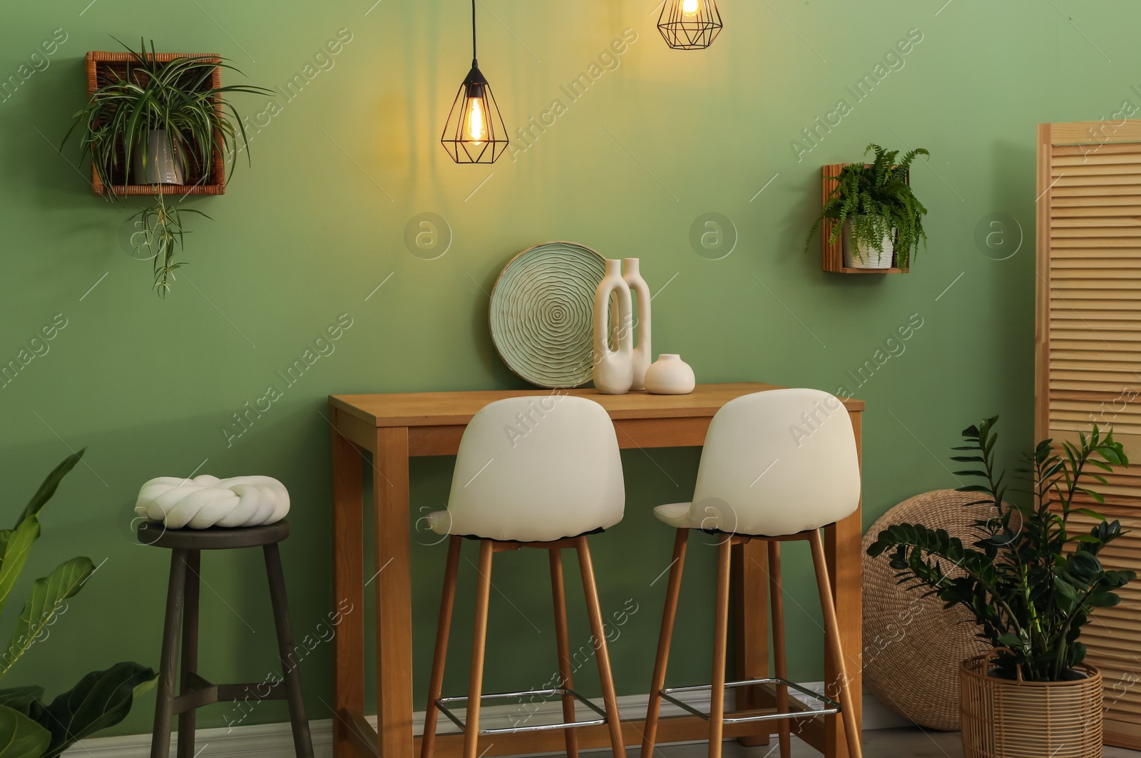 Photo of Bar stools, table and plants in room. Stylish interior design