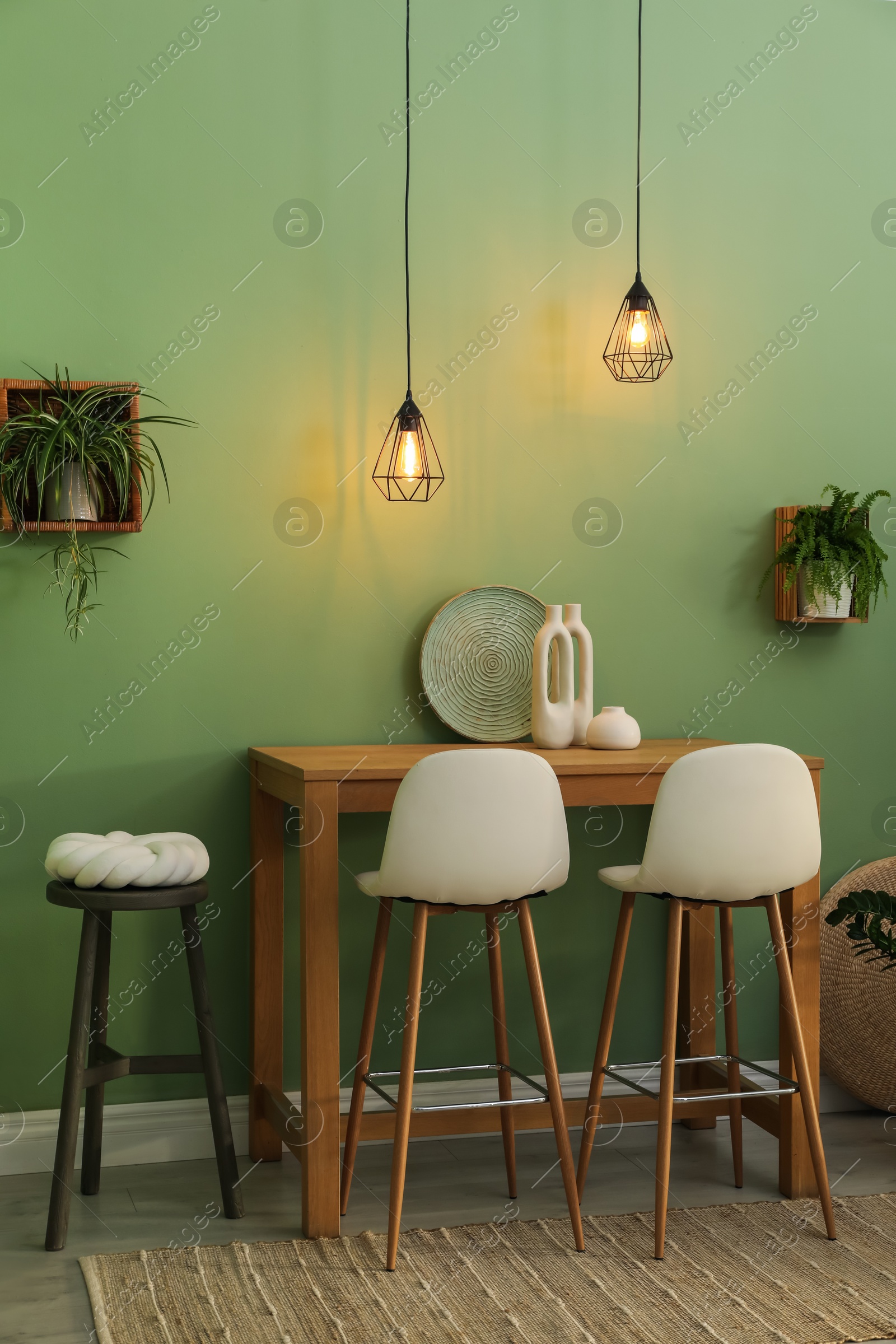 Photo of Bar stools, table and plants in room. Stylish interior design