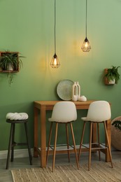 Bar stools, table and plants in room. Stylish interior design