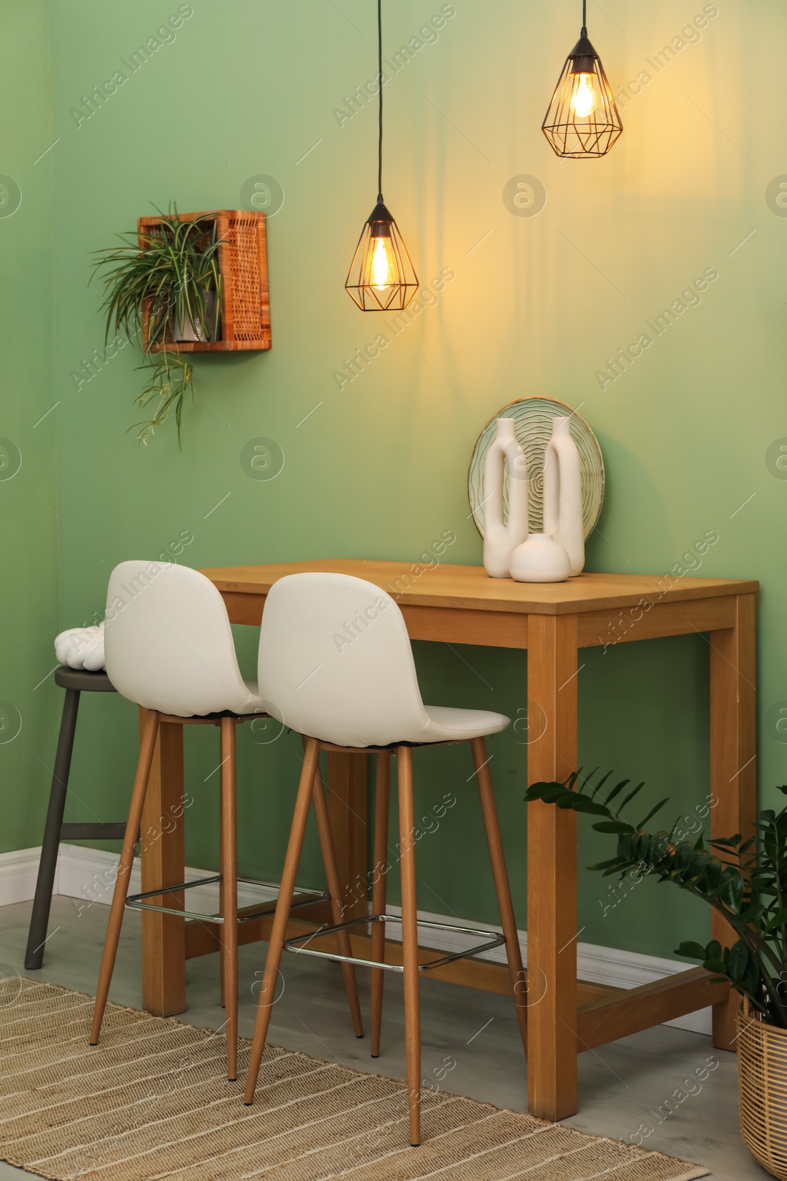 Photo of Bar stools, table and plants in room. Stylish interior design