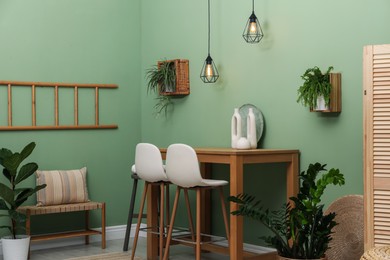 Bar stools, table and plants in room. Stylish interior design