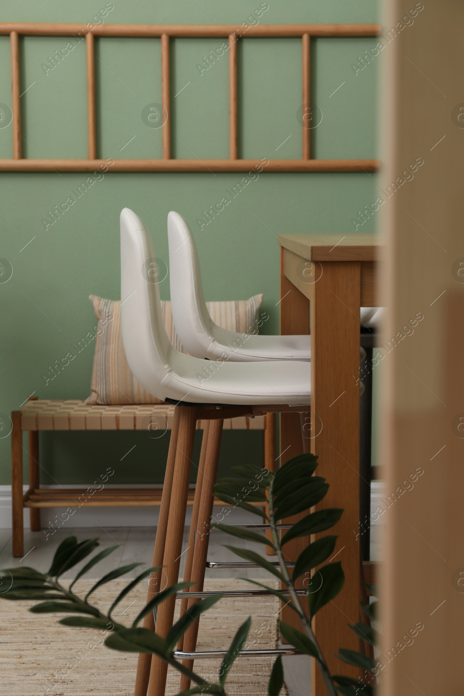 Photo of Bar stools, table and plant in room. Stylish interior design