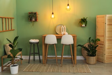 Bar stools, table and plants in room. Stylish interior design