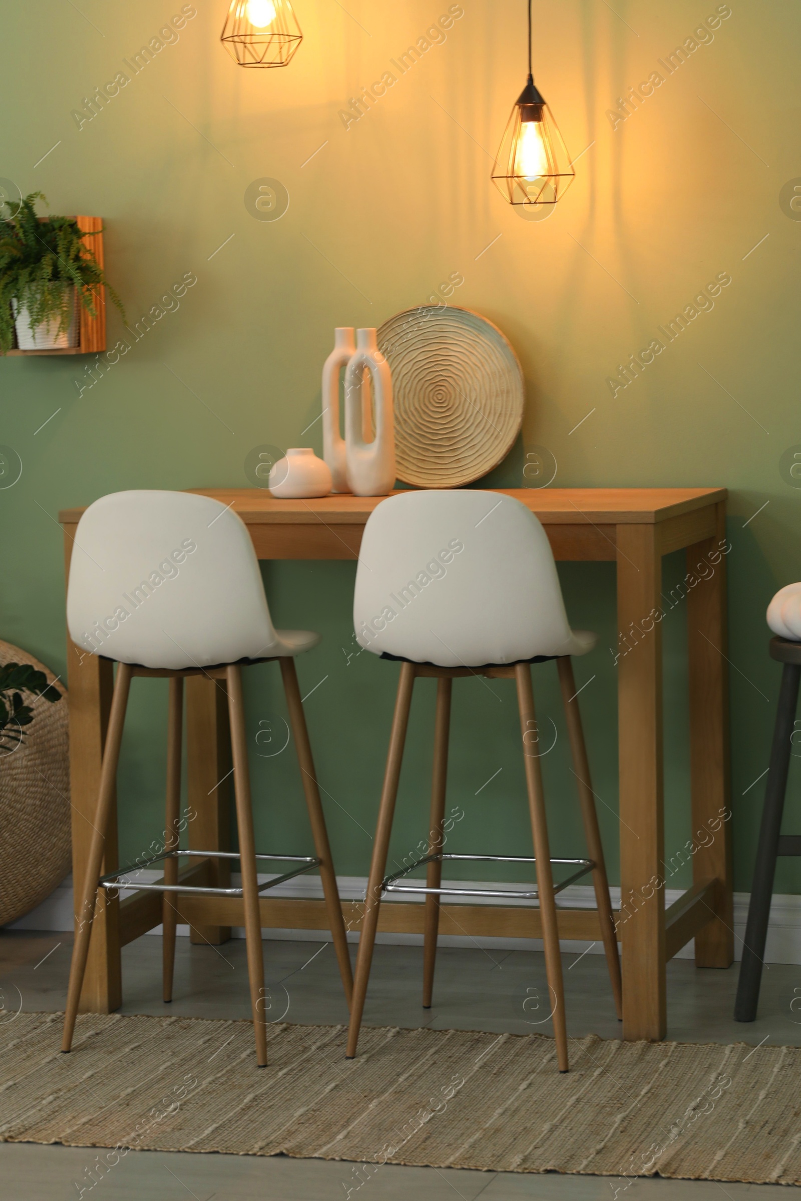 Photo of Bar stools, table and plant in room. Stylish interior design