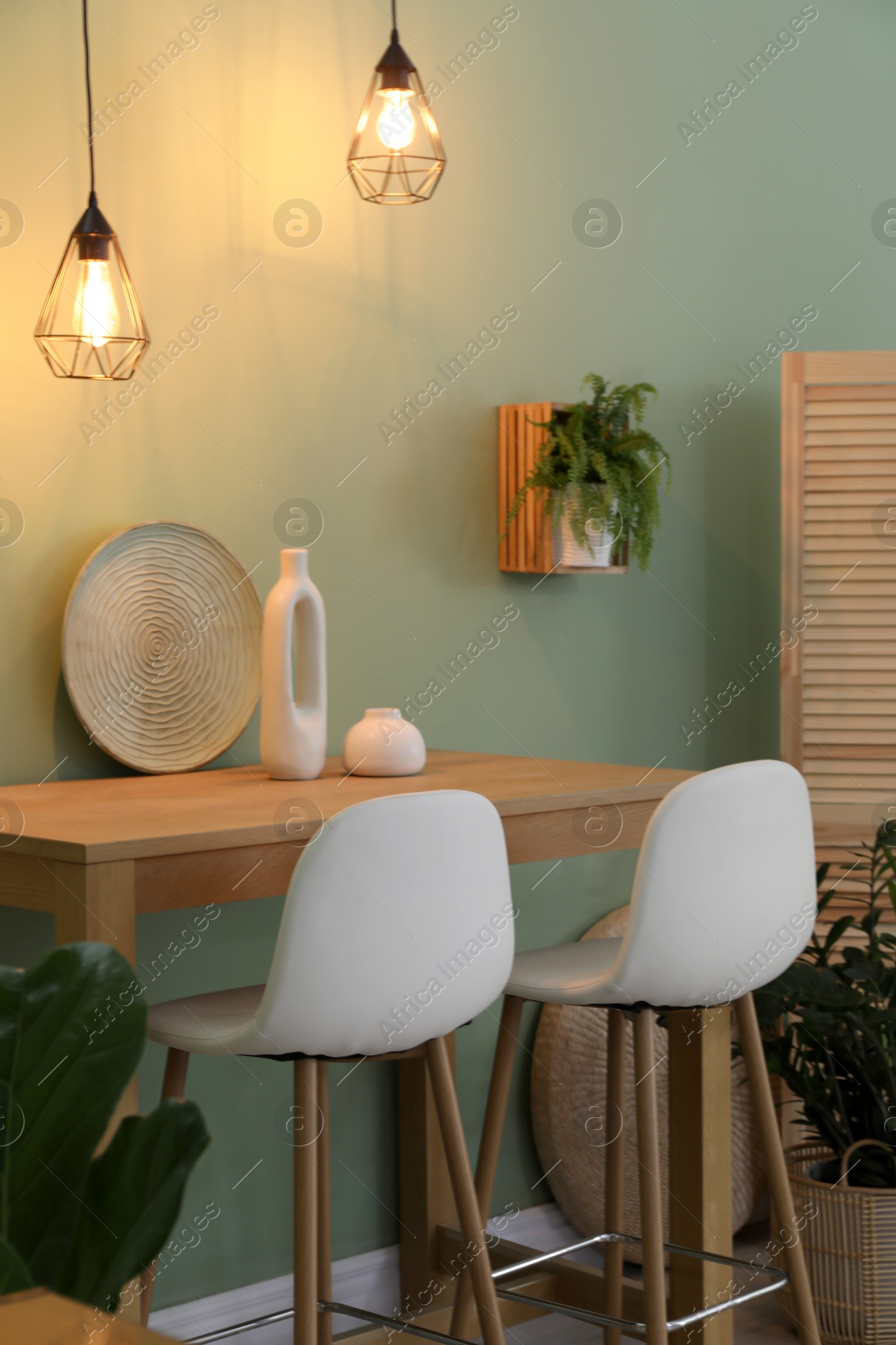 Photo of Bar stools, table and plants in room. Stylish interior design