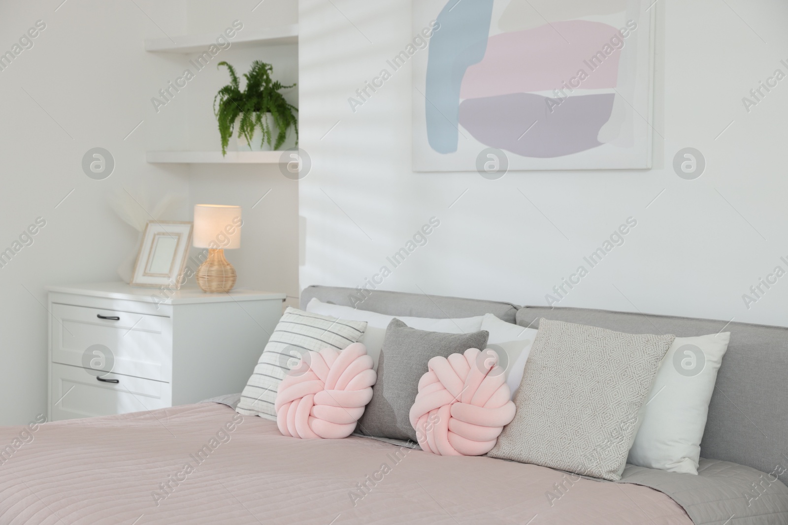 Photo of Large bed with soft pillows in room. Stylish bedroom interior