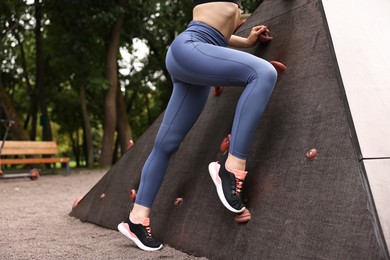 Photo of Woman wearing sports leggings near climbing wall outdoors, closeup. Space for text