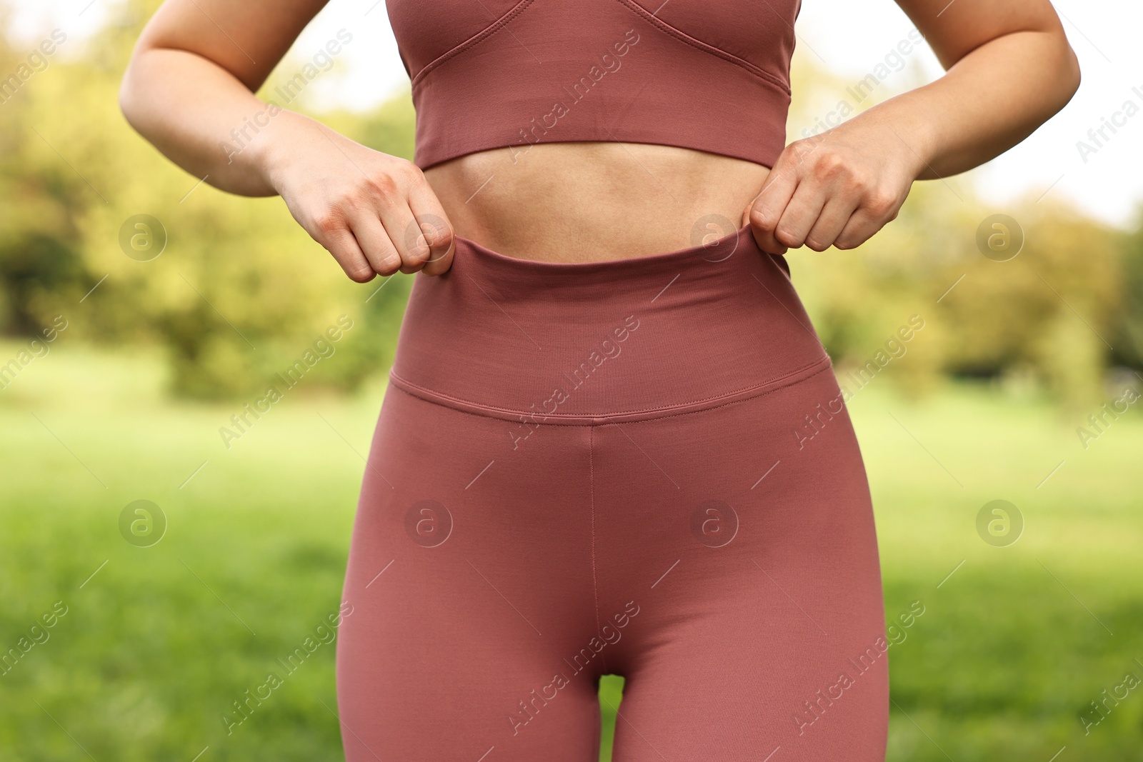 Photo of Woman wearing stylish sports leggings outdoors, closeup