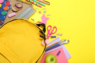 Photo of School backpack and stationery on yellow background, flat lay. Space for text