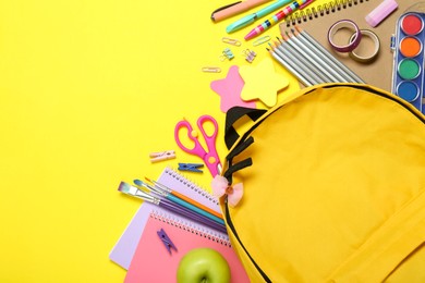 Photo of School backpack and stationery on yellow background, flat lay. Space for text