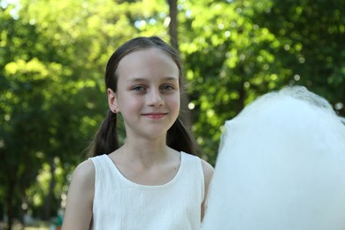 Photo of Portrait of little girl with sweet cotton candy in park