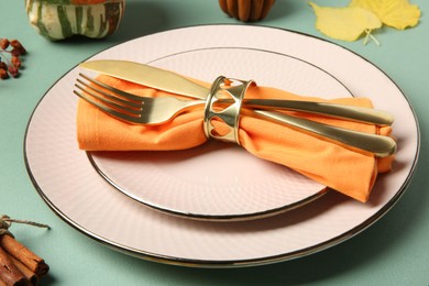 Photo of Beautiful table setting with autumn decor on turquoise background, closeup