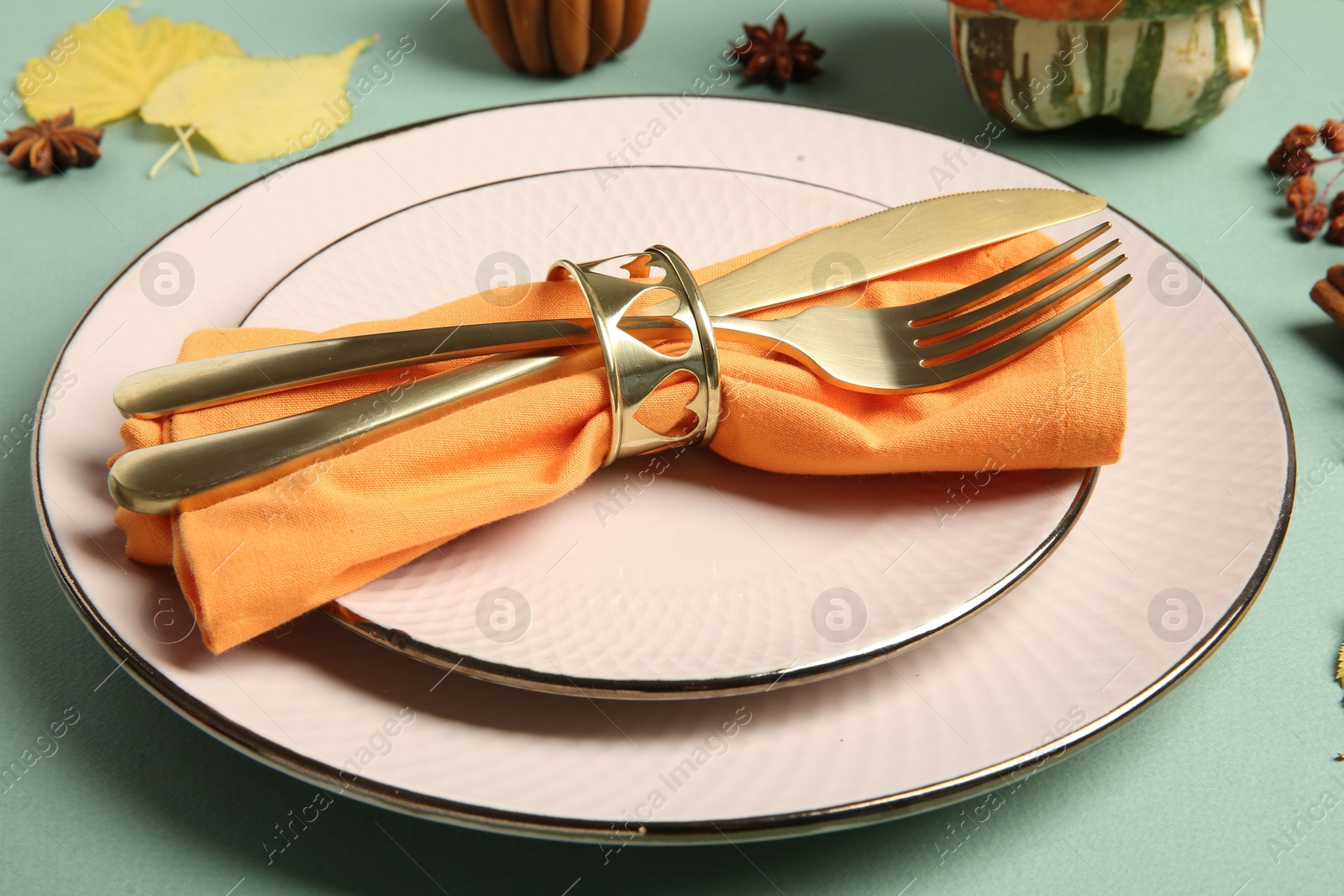 Photo of Beautiful table setting with autumn decor on turquoise background, closeup