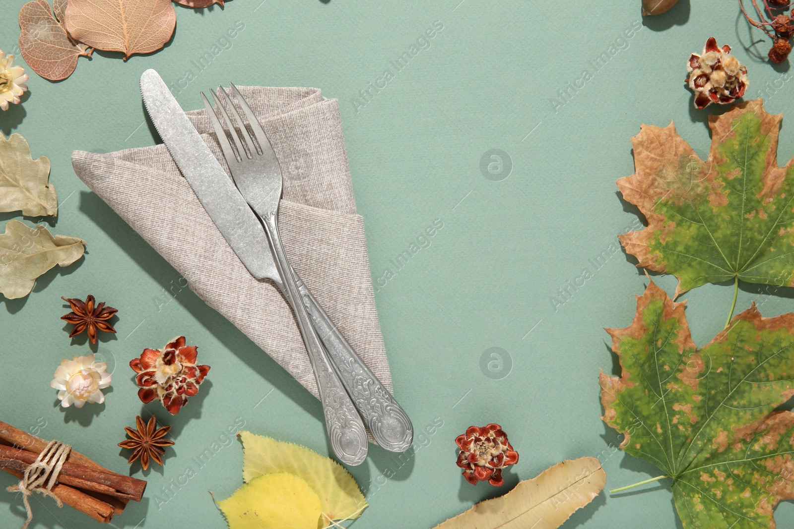 Photo of Frame made of beautiful table setting with autumn decor on turquoise background, flat lay. Space for text