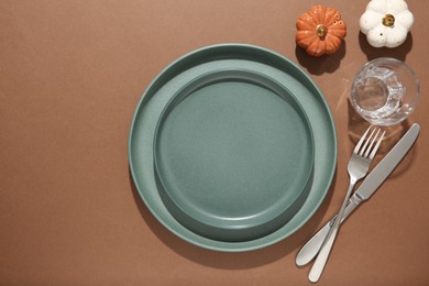 Beautiful table setting with autumn decor on brown background, flat lay. Space for text