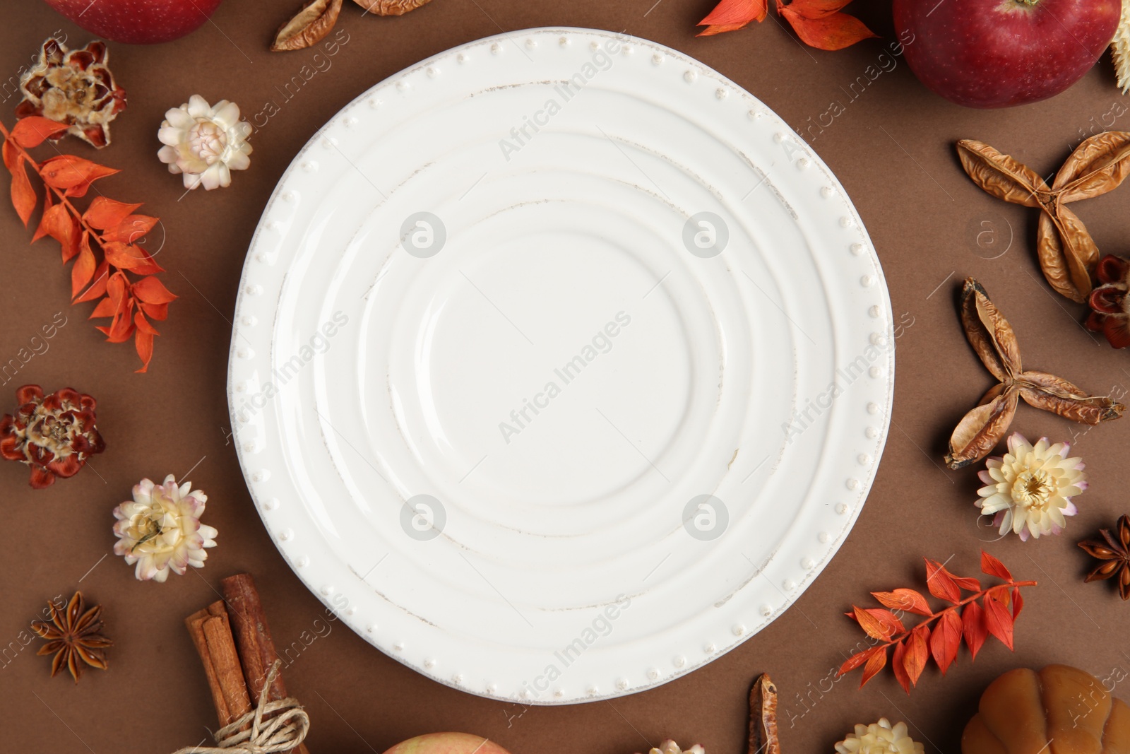 Photo of Stylish table setting. Plate and autumn decor on brown background, flat lay