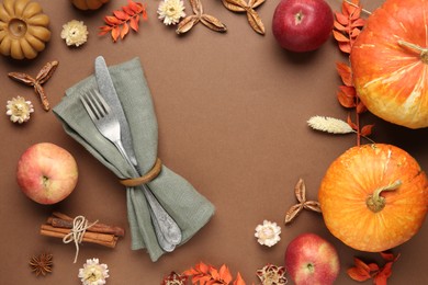 Frame made of beautiful table setting with autumn decor on brown background, flat lay. Space for text