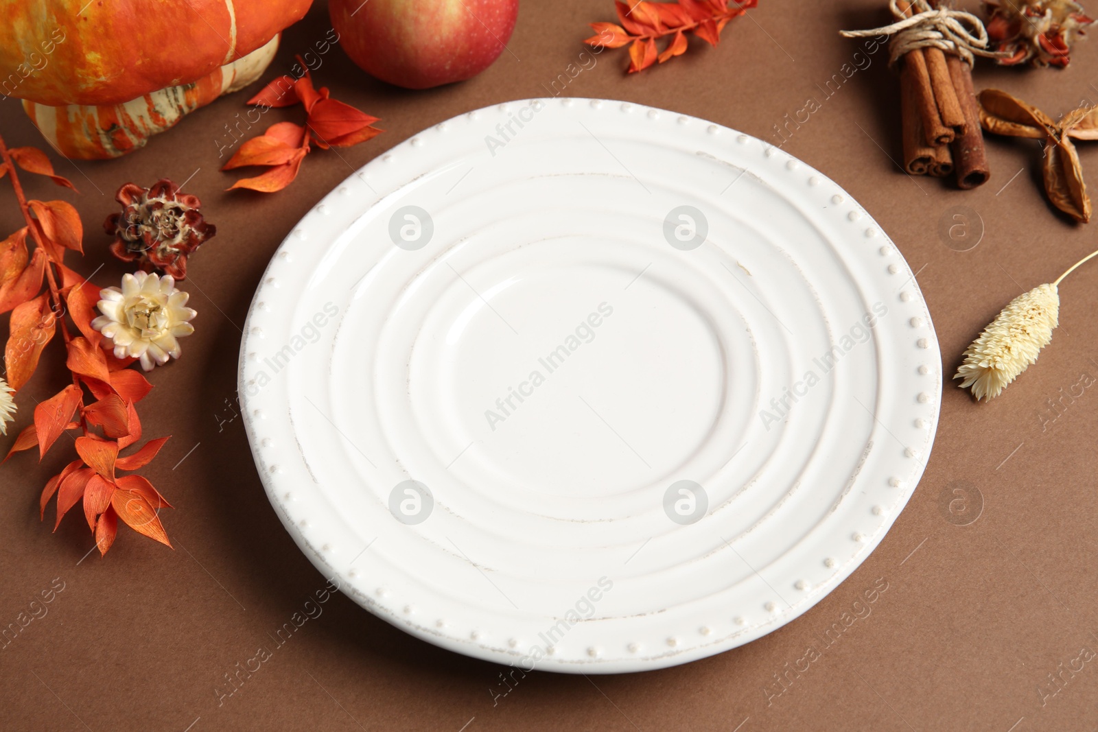 Photo of Stylish table setting. Plate and autumn decor on brown background