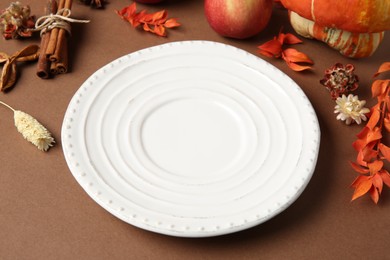 Photo of Stylish table setting. Plate and autumn decor on brown background