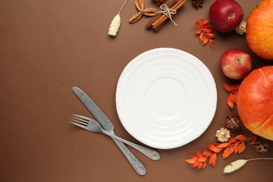 Beautiful table setting with autumn decor on brown background, flat lay. Space for text