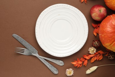 Beautiful table setting with autumn decor on brown background, flat lay