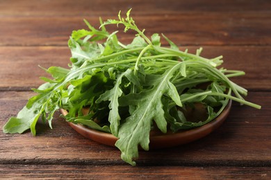 Photo of Fresh green arugula leaves on wooden table, closeup