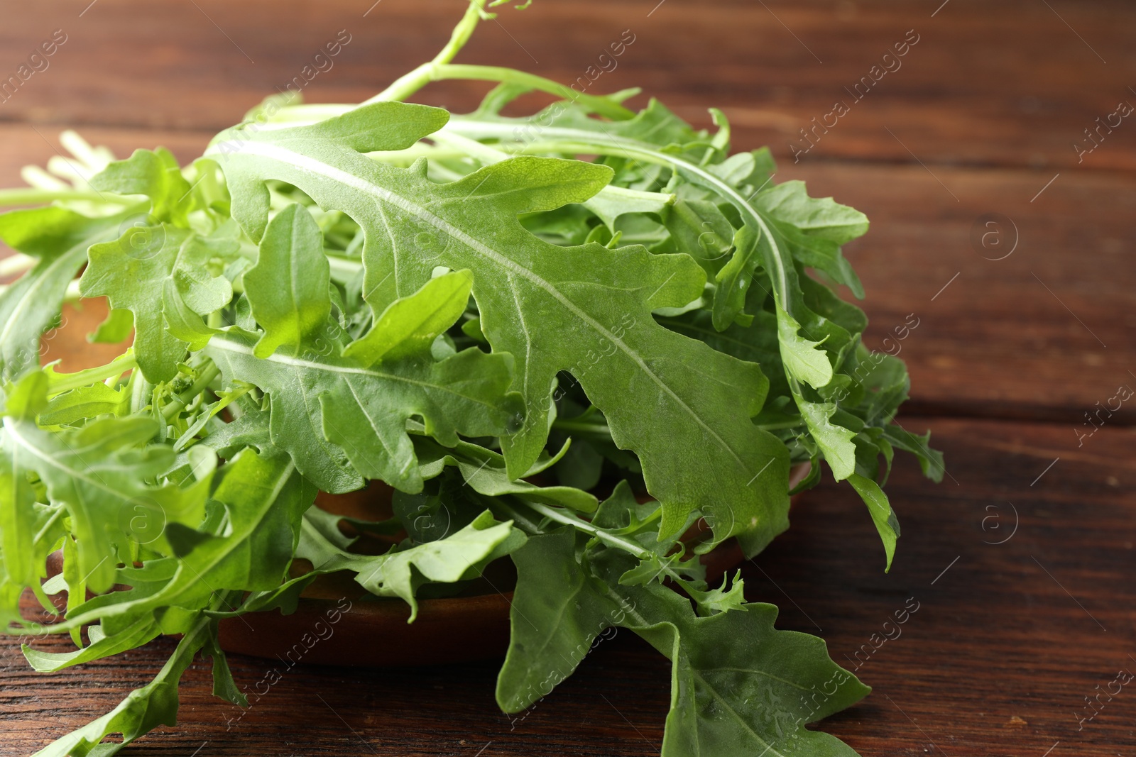 Photo of Fresh green arugula leaves on wooden table, closeup