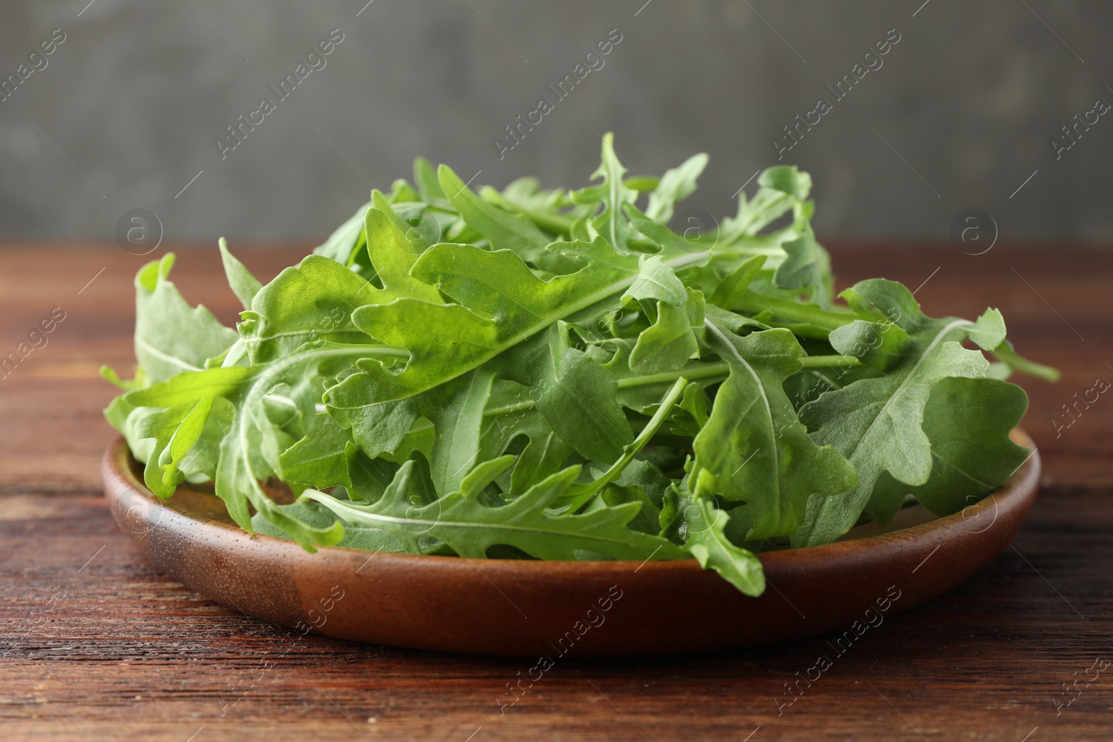 Photo of Fresh green arugula leaves on wooden table, closeup