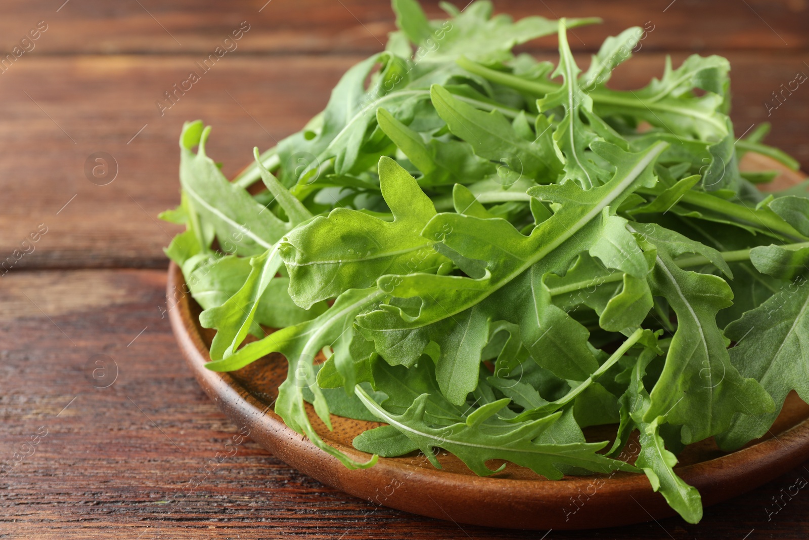 Photo of Fresh green arugula leaves on wooden table, closeup