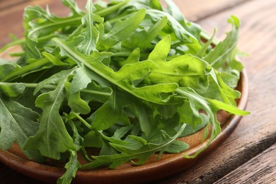 Photo of Fresh green arugula leaves on wooden table, closeup