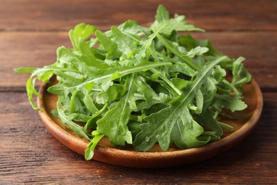 Photo of Fresh green arugula leaves on wooden table, closeup