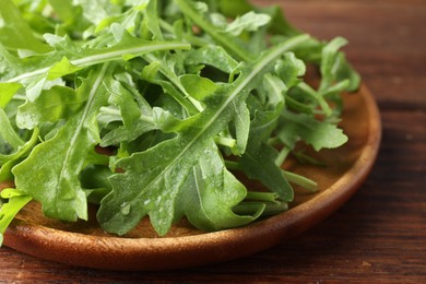 Photo of Fresh green arugula leaves on wooden table, closeup