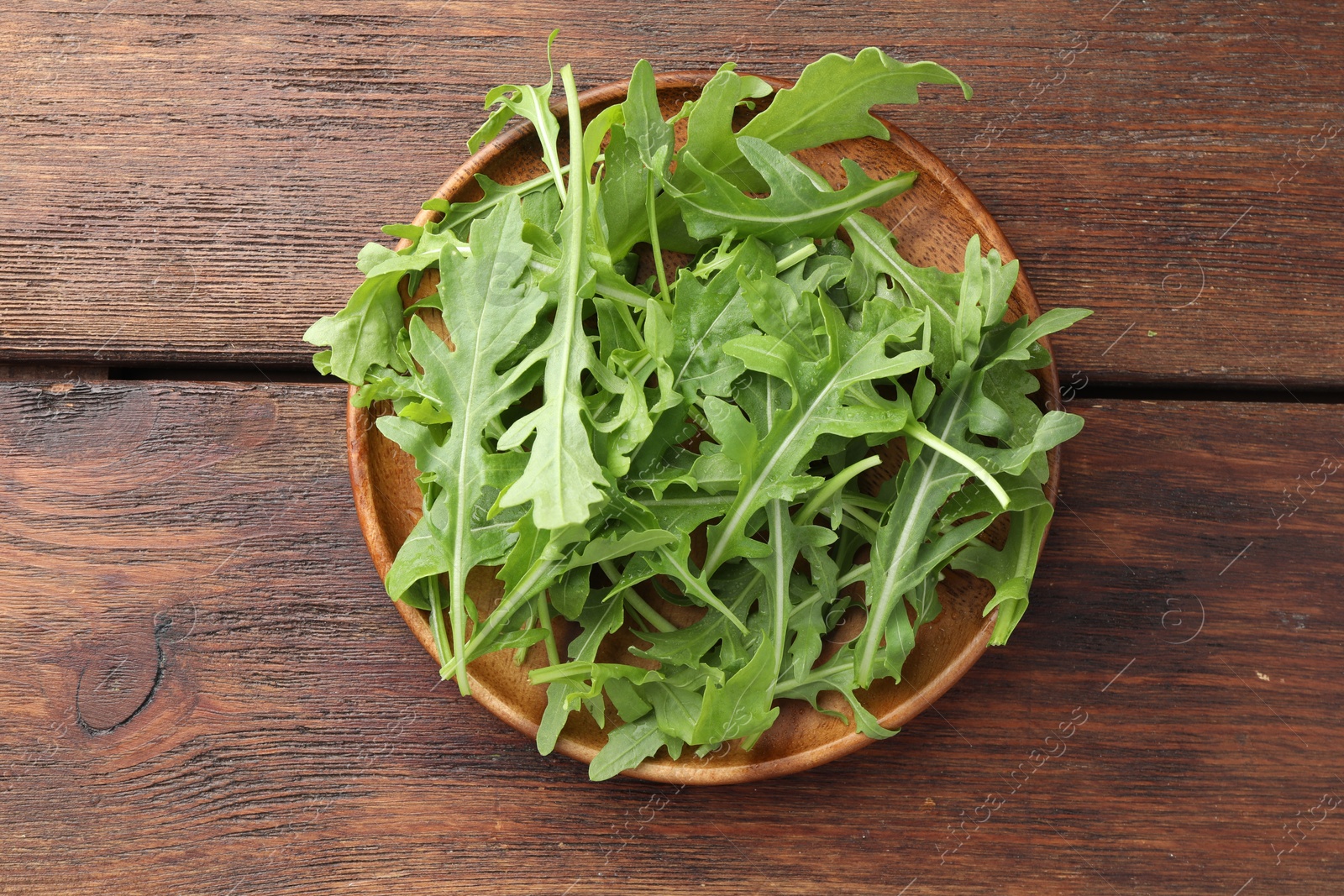 Photo of Fresh green arugula leaves on wooden table, top view